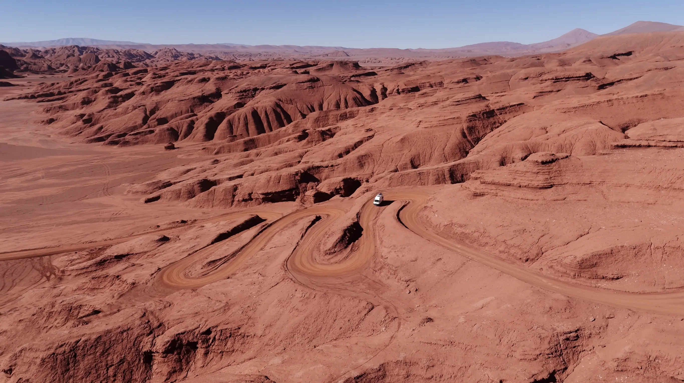 Prise de vue aérienne du van aménagé sur une piste de terre ocre serpentant dans le Desierto del Diablo dans la Puna, une région du nord de l'Argentine